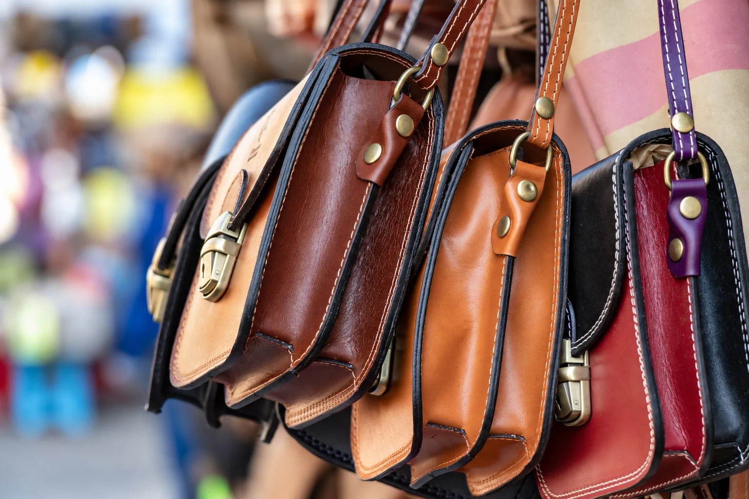 Three assorted-color leather crossbody bags hanging close together