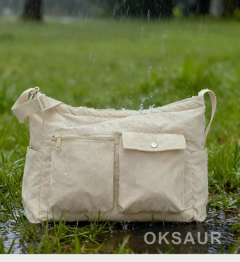 Light beige crossbody bag shown outdoors with water droplets on its fabric