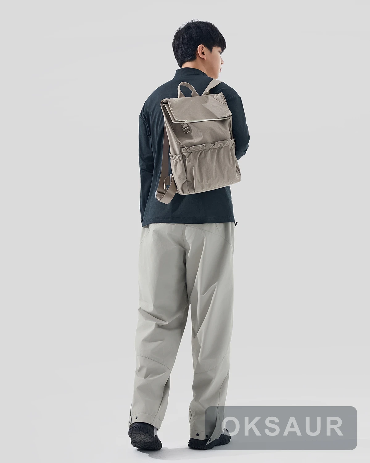 Warm grey pocket backpack worn from the rear
